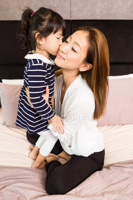 Маленька дівчинка цілує матір вдома — стокове фото