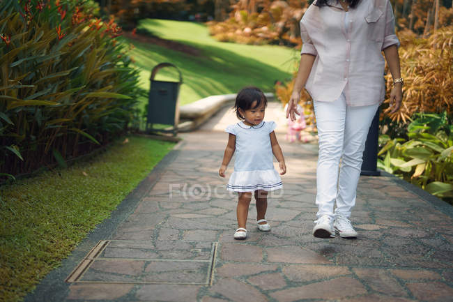 Cute asian mother and daughter walking in park — Stock Photo