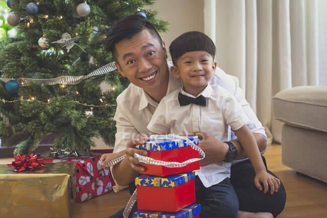 Father and son sit on the floor and open Christmas presents — Stock Photo