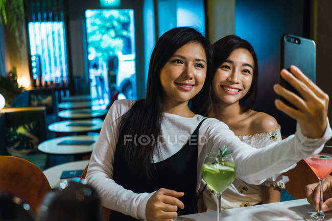 Young asian friends taking selfie in comfortable bar — Stock Photo