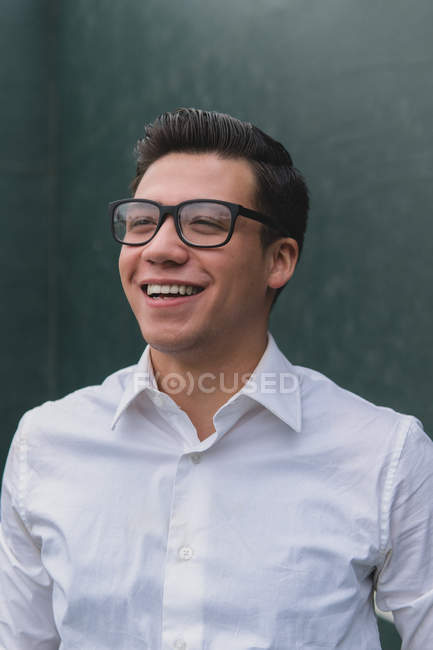 Atractivo joven sonriendo mirando lejos de la cámara - foto de stock