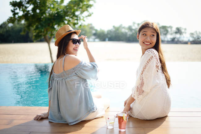 Hermosa joven asiático mujeres relajarse cerca de piscina - foto de stock