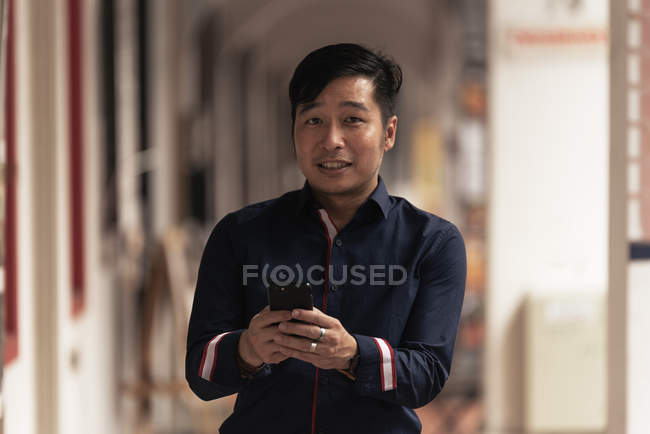 Feliz asiático jovem homem usando smartphone — Fotografia de Stock