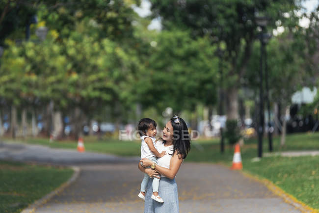 Joven madre con asiático hija en parque - foto de stock