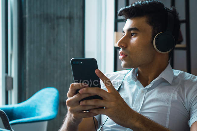 Hombre de negocios adulto joven con auriculares en la oficina - foto de stock