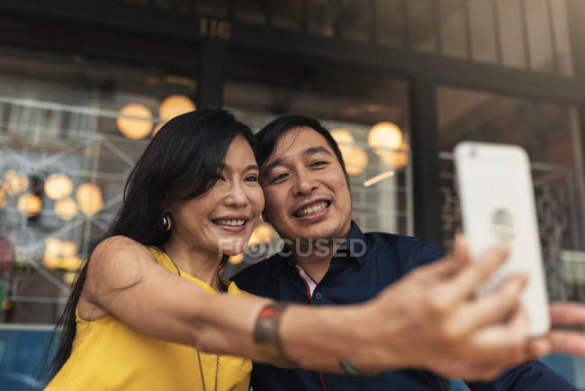 Happy young asian couple taking selfie in cafe — Stock Photo
