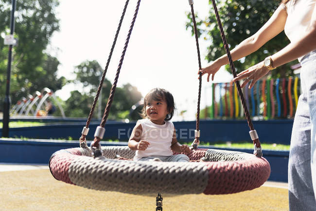 Jeune mère avec asiatique fille à aire de jeux — Photo de stock