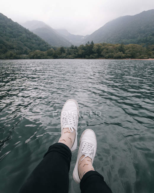 Immagine ritagliata delle gambe di fronte al lago — Foto stock