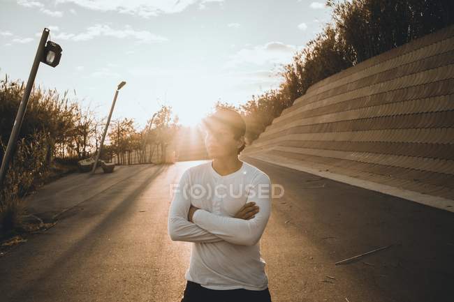 Junger asiatischer Mann steht bei Sonnenuntergang mit verschränkten Armen — Stockfoto