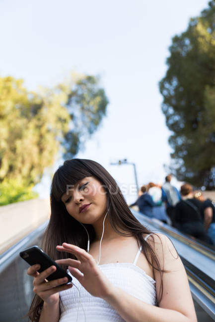 Cute eurasian woman listening to music in park — Stock Photo