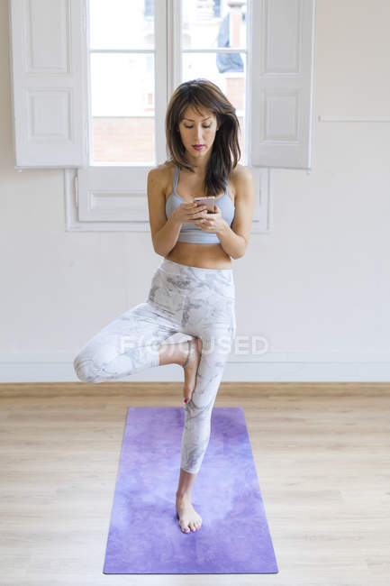 Young asian woman standing on one leg while using smartphone — Stock Photo