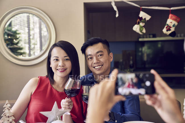Feliz asiático familia celebrando navidad juntos y tomando foto en mesa - foto de stock