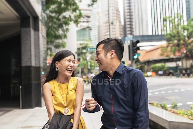 Happy young asian couple laughing on city street — Stock Photo