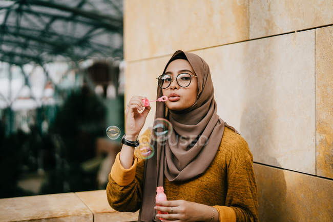 Young asian muslim woman in hijab making bubbles — Stock Photo