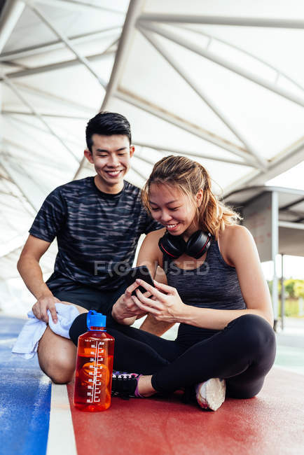 Азиатская пара сидит на полу и использует смартфон — стоковое фото