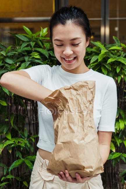 Jeune attrayant asiatique femme tenant sac en papier — Photo de stock