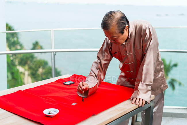 Старий азіатський чоловік малює ієрогліфи каліграфії — стокове фото