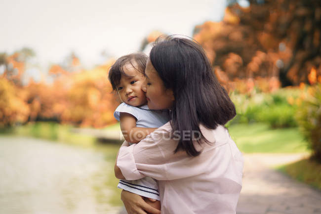 Carino asiatico madre e figlia abbraccio in parco — Foto stock
