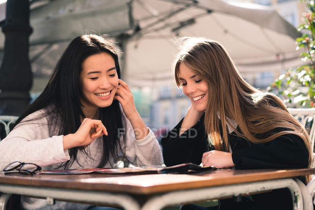 Belos amigos que procuram um mapa nas ruas da Espanha sentados em uma cafeteria — Fotografia de Stock