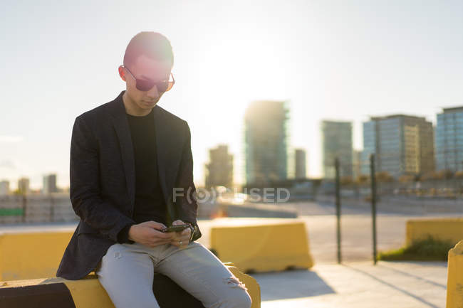 Young asian man using smartphone on parking — Stock Photo