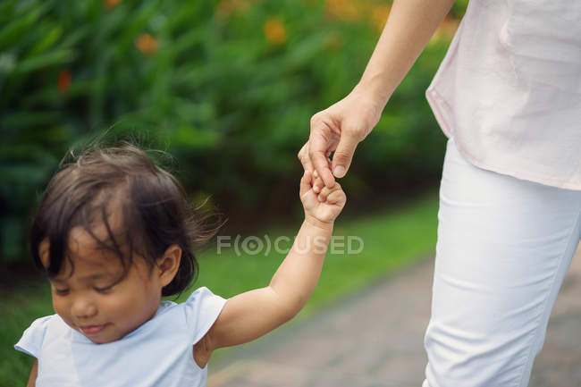 Lindo asiático madre y hija cogida de la mano en parque - foto de stock