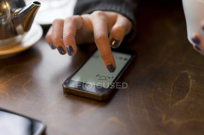 Обрезанный образ женщины с помощью смартфона в кафе — стоковое фото