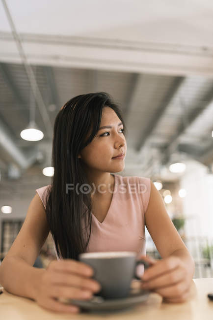Young asian successful business woman with coffee in modern office — Stock Photo