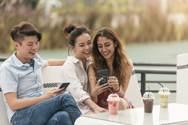 Group of friends at a restaurant, using devices — Stock Photo