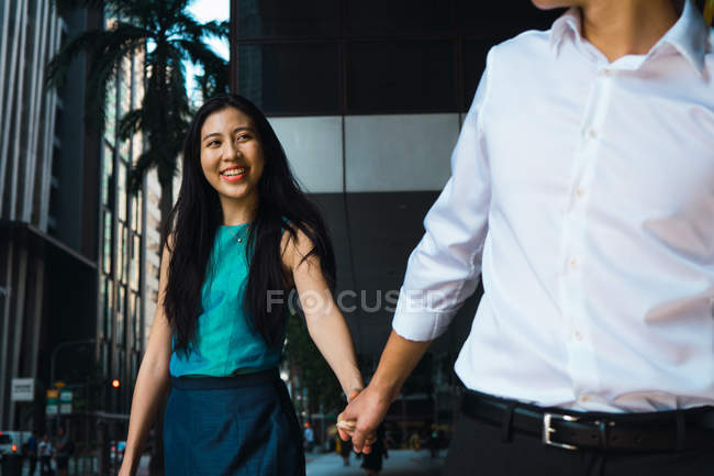 Young adult business couple walking hand in hand — Stock Photo
