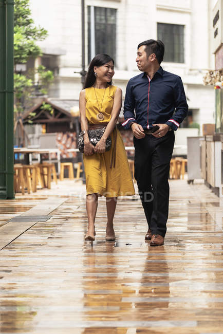 Счастливая молодая азиатская пара, идущая вместе по улице — стоковое фото