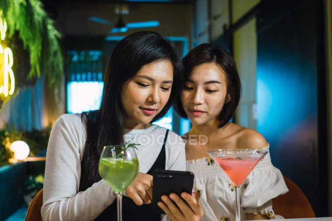 Jovem asiático amigos usando inteligente no confortável bar — Fotografia de Stock
