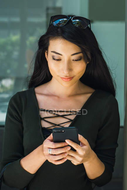 Retrato de joven mujer asiática usando smartphone - foto de stock