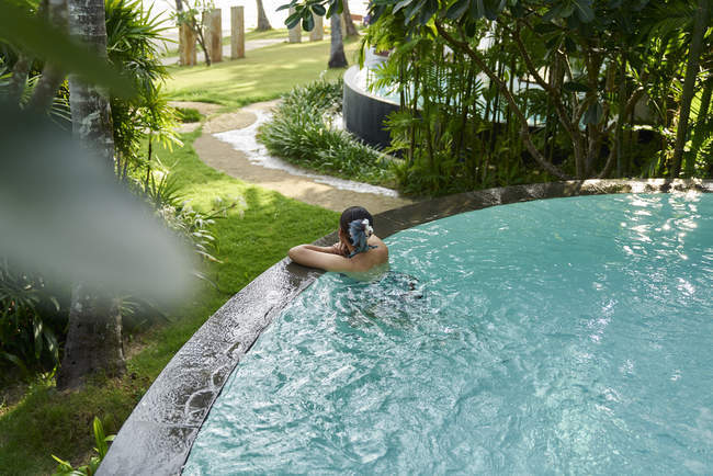 Молодая азиатка отдыхает в бассейне, вид сзади — стоковое фото