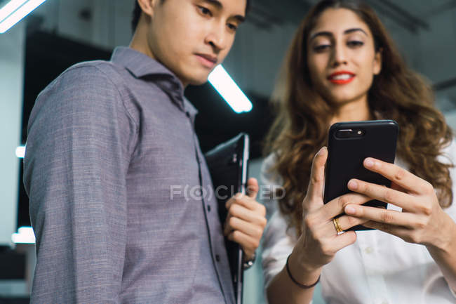 Junge asiatische Geschäftsleute mit Geräten im modernen Büro — Stockfoto