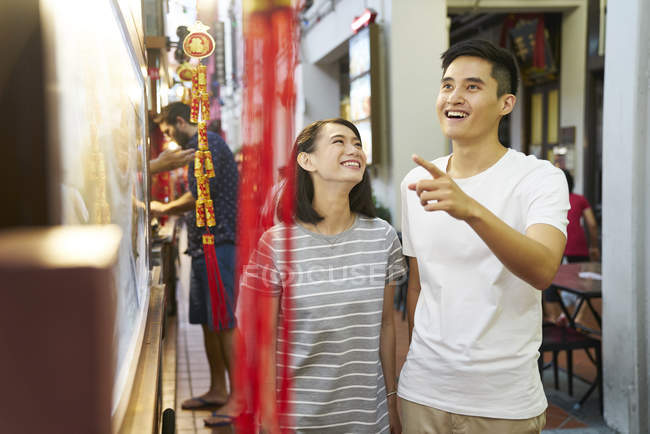 Молодые азиатские люди покупки, мужчина указывая — стоковое фото