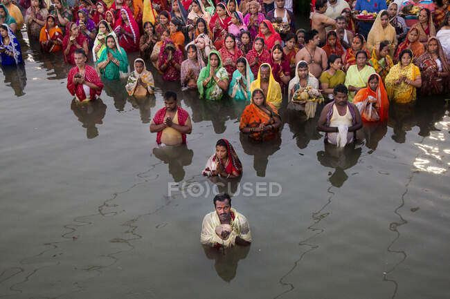 A triangle formed by the Devotees standing waist high in cold water facing towards the sun offering prayers to SUN GOD. People are ready go anywhere and do anything in Devotion towards the GOD. — Stock Photo