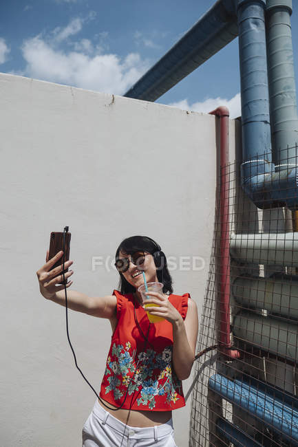 Mulher asiática com fones de ouvido tirar selfie contra a parede — Fotografia de Stock