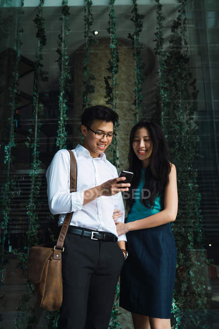 Молодые взрослые деловые пары, использующие смартфон на открытом воздухе — стоковое фото