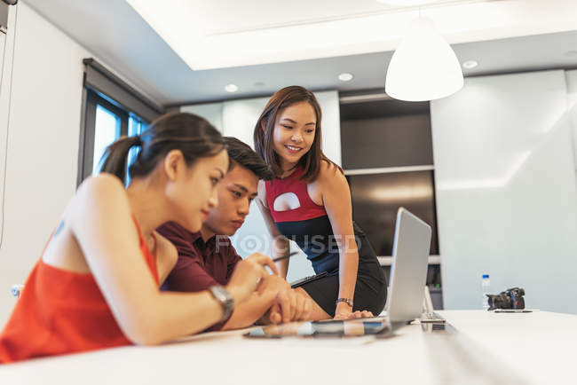Young attractive asian people working in modern office — Stock Photo