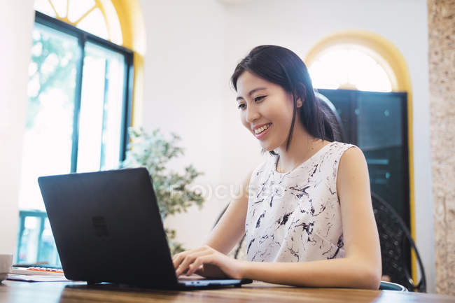 Young asian woman using laptop in creative modern office — Stock Photo