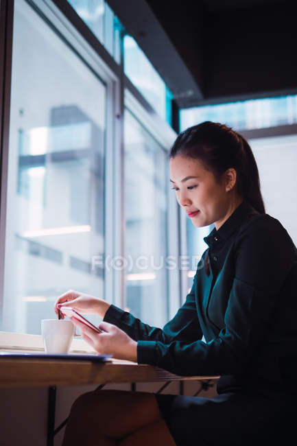 Молода бізнес-леді зі смартфоном в сучасному офісі — стокове фото