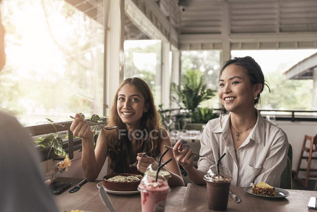 Дві молоді красиві азіатські жінки проводять час у кафе — стокове фото
