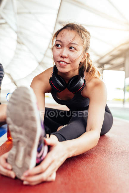Chinês mulher exercitando enquanto sentado no chão — Fotografia de Stock