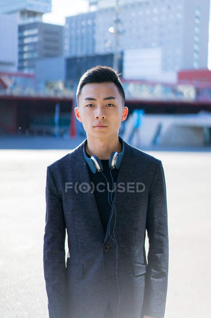 Retrato de joven asiático hombre en traje y auriculares - foto de stock