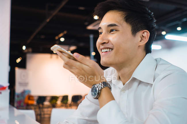 Молодой азиатский бизнесмен, использующий смартфон в современном офисе — стоковое фото