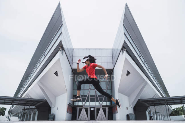 Junge asiatische sportliche Frau springt in die Luft — Stockfoto
