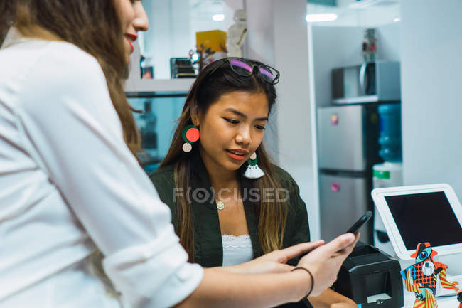 Jóvenes asiático negocios mujeres usando smartphone en moderno oficina - foto de stock