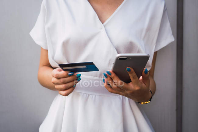 Image recadrée de jeune belle femme asiatique tenant smartphone et carte de crédit — Photo de stock