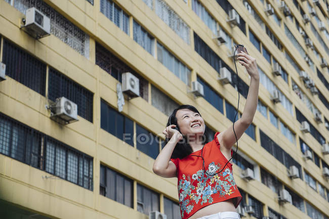 Азиатская туристическая женщина делает селфи против дома днем — стоковое фото