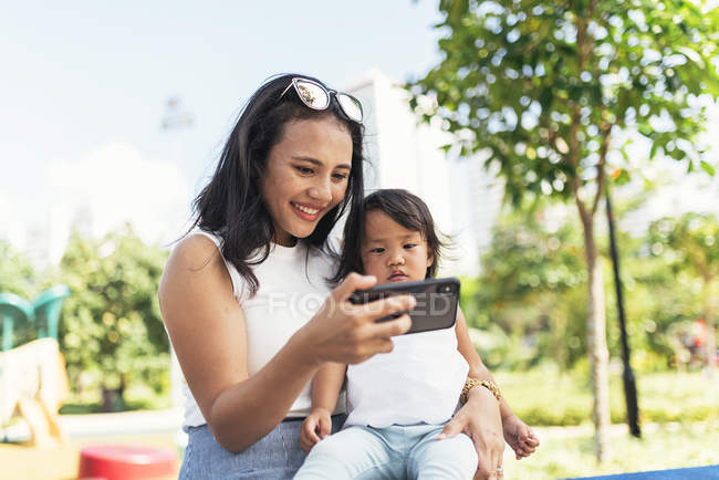 Giovane madre con figlia asiatica prendendo selfie — Foto stock